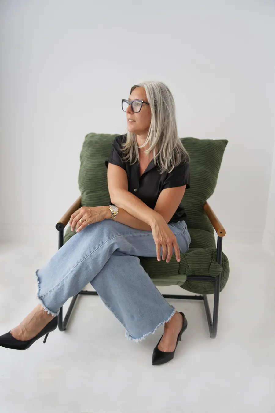 Jamie Mazuryk in a green armchair, looking out a window